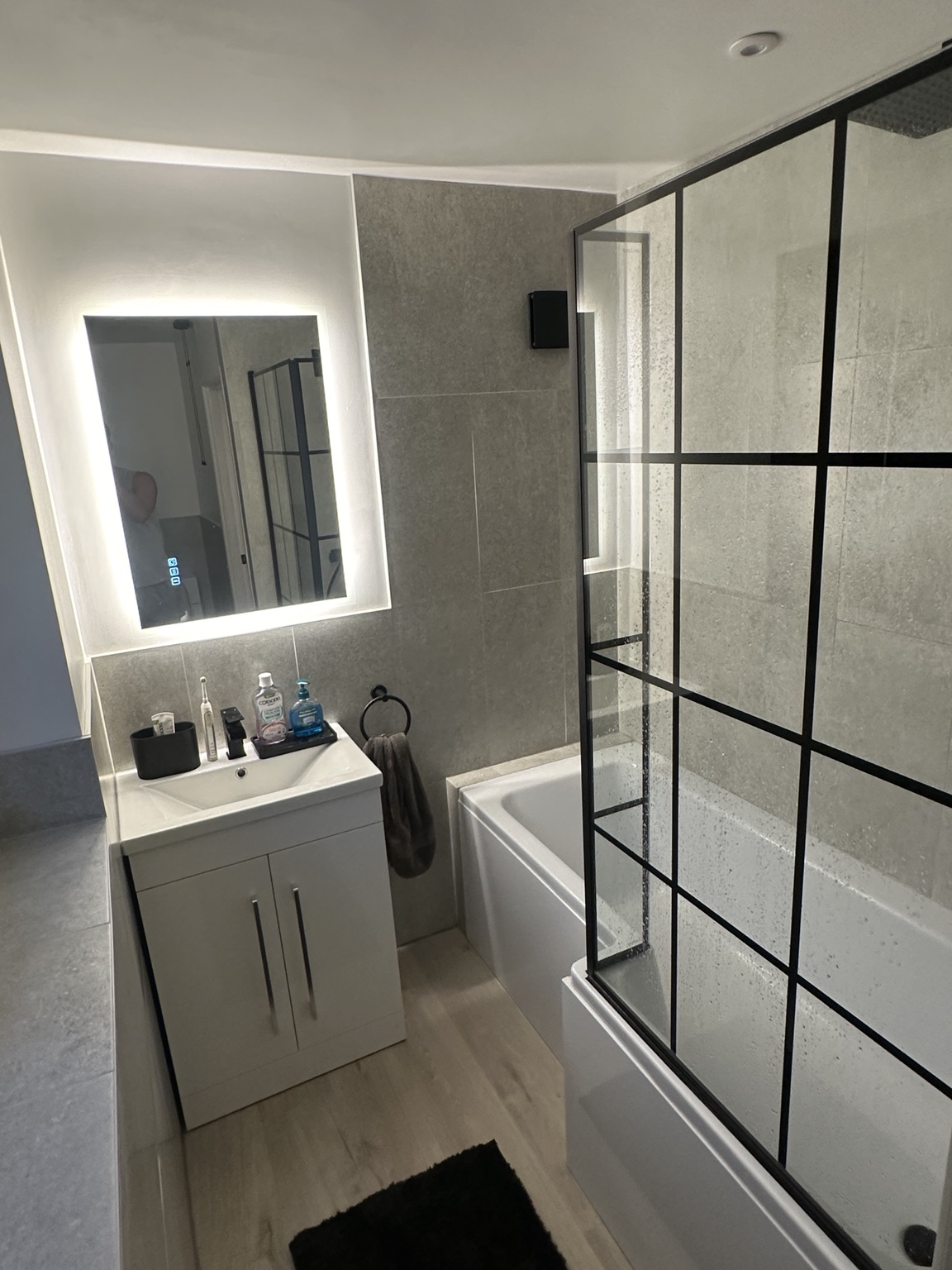 Finished bathroom with electrical lighting and illuminated mirror
